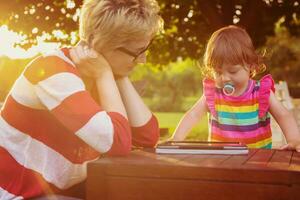 mom and her little daughter using tablet computer photo