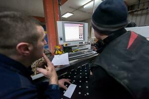 carpenters calculating and programming a cnc wood working machine photo