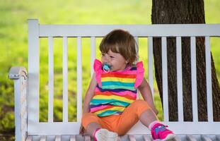 cute little girl sitting on wooden bench photo