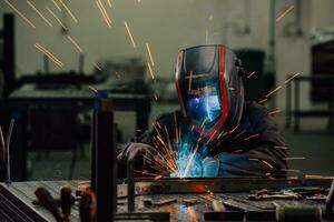 Professional Heavy Industry Welder Working Inside factory, Wears Helmet and Starts Welding. Selective Focus photo