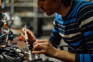 Industrial worker man soldering cables of manufacturing equipment in a factory. Selective focus photo