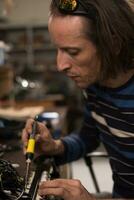 Industrial worker man soldering cables of manufacturing equipment in a factory. Selective focus photo