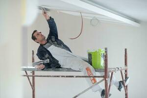 construction worker plastering on gypsum ceiling photo
