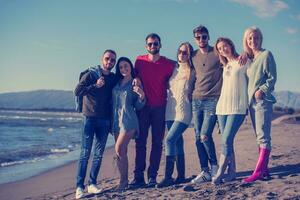 portrait of friends having fun on beach during autumn day photo