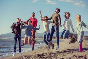 young friends jumping together at autumn beach photo