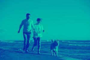 pareja con perro divirtiéndose en la playa el día del otoño foto