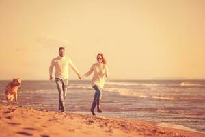 pareja con perro divirtiéndose en la playa el día del otoño foto