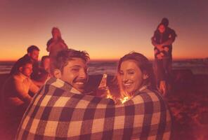 Couple enjoying with friends at sunset on the beach photo