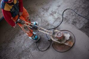 worker performing and polishing sand and cement screed floor photo