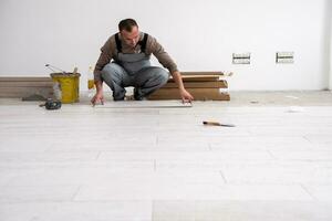 worker installing the ceramic wood effect tiles on the floor photo