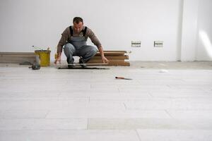 worker installing the ceramic wood effect tiles on the floor photo