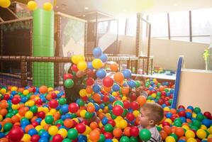 young mom playing with kids in pool with colorful balls photo