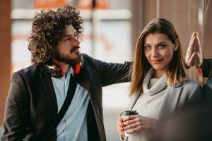 Two serious businessmen drinking coffee to take away. Man and middle-aged woman in official shirt standing outside. Coffee break concept photo