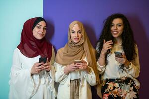 Group portrait of beautiful muslim women two of them in fashionable dress with hijab isolated on colorful background representing modern islam fashion and ramadan kareem concept photo