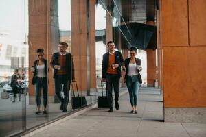 Business man and business woman talking and holding luggage traveling on a business trip, carrying fresh coffee in their hands.Business concept photo