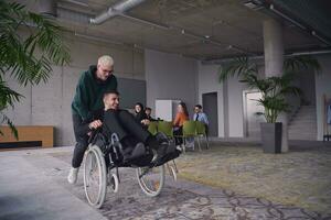 A young entrepreneur and his colleague, who is a person with a disability, fun together through a large, modern office, demonstrating the power of teamwork, inclusivity, and determination as they drive the wheelchair photo