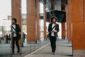 Trendy businessman with leather briefcase in financial district using smartphone while listening audio songs headphones drinking coffee photo