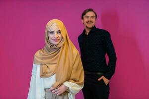 Portrait of happy young muslim couple standing isolated on pink background photo