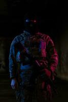 Army soldier in Combat Uniforms with an assault rifle and combat helmet night mission dark background. Blue and purple gel light effect. photo