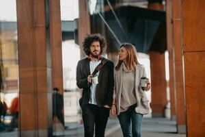 Business man and business woman talking and holding luggage traveling on a business trip, carrying fresh coffee in their hands.Business concept photo