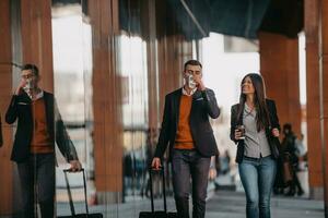 hombre de negocios y mujer de negocios hablando y sosteniendo equipaje viajando en un viaje de negocios, llevando café recién hecho en sus manos.concepto de negocio foto