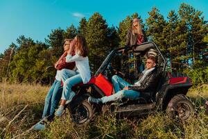 Group young happy people enjoying beautiful sunny day while driving a off road buggy car on mountain nature photo