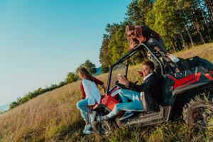 Group young happy people enjoying beautiful sunny day while driving a off road buggy car on mountain nature photo