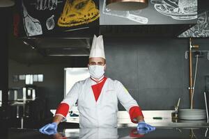 chef cook wearing face protective medical mask for protection from coronavirus photo