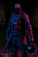 Army soldier in Combat Uniforms with an assault rifle and combat helmet night mission dark background. Blue and purple gel light effect. photo