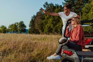 Young happy excited couple enjoying beautiful sunny day while driving a off road buggy car on mountain nature photo