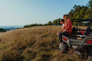 Young happy excited couple enjoying beautiful sunny day while driving a off road buggy car on mountain nature photo