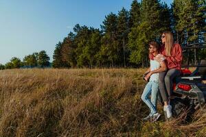 Young happy excited couple enjoying beautiful sunny day while driving a off road buggy car on mountain nature photo