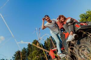 Young happy excited couple enjoying beautiful sunny day while driving a off road buggy car on mountain nature photo