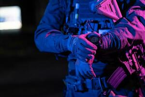 Modern warfare soldier checking navigation, time and other information on a smartwatch. Dark night black background. photo