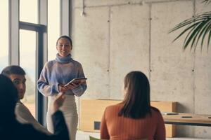 A group of young business professionals in a modern office attentively listens to colleague presentation, showcasing a dynamic and collaborative atmosphere as they exchange ideas and strive for success. photo