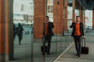 Going to airport terminal. Confident businessman traveler walking on city streets and pulling his suitcase drinking coffee and speaking on smartphone photo