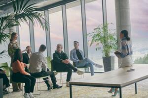 A group of young business professionals in a modern office attentively listens to colleague presentation, showcasing a dynamic and collaborative atmosphere as they exchange ideas and strive for success. photo