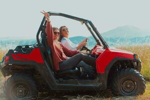 Two young happy excited women enjoying beautiful sunny day while driving a off road buggy car on mountain nature photo