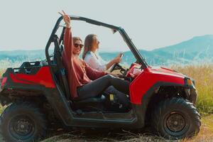 Two young happy excited women enjoying beautiful sunny day while driving a off road buggy car on mountain nature photo