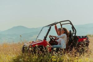 Two young happy excited women enjoying beautiful sunny day while driving a off road buggy car on mountain nature photo