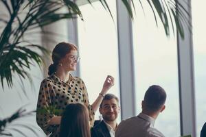 A group of young business professionals in a modern office attentively listens to colleague presentation, showcasing a dynamic and collaborative atmosphere as they exchange ideas and strive for success. photo