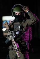 Army soldier in Combat Uniforms with an assault rifle and combat helmet night mission dark background. Blue and purple gel light effect. photo