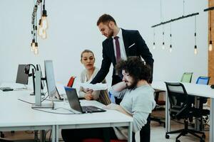 Group of multi-ethnic colleagues working on desktop computers, laptop and sharing their ideas in a modern office space.Young influencers work on online marketing projects. photo