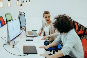 Two colleagues working on a project in modern startup offices. Guy with afro haircut and a female blonde employee working at the office. photo