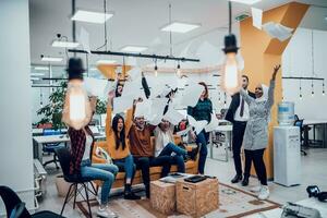 Group of business people throwing paper in air at modern startup office, team success and job done concept photo