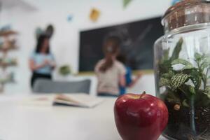 Biology and biochemistry classes. A close-up photo of a bottle containing a green plant and a ripe apple next to the bottle