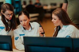 Group of female security operators working in a data system control room Technical Operators Working at workstation with multiple displays, security guards working on multiple monitors in surveillan photo