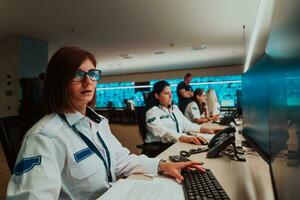 Group of female security operators working in a data system control room Technical Operators Working at workstation with multiple displays, security guards working on multiple monitors in surveillan photo