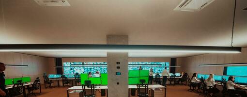 Group of Security data center operators working in a CCTV monitoring room looking on multiple monitors Officers Monitoring Multiple Screens for Suspicious Activities Team working on the System Contr photo