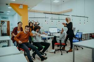 Team building and office fun. Young cheerful businesspeople in smart casual wear having fun while racing on office chairs and smiling. photo